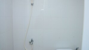 A bathroom with white tiles, a shower, and a toilet. - Comfort and Spacious Studio Room Bassura City Apartment (Jakarta)