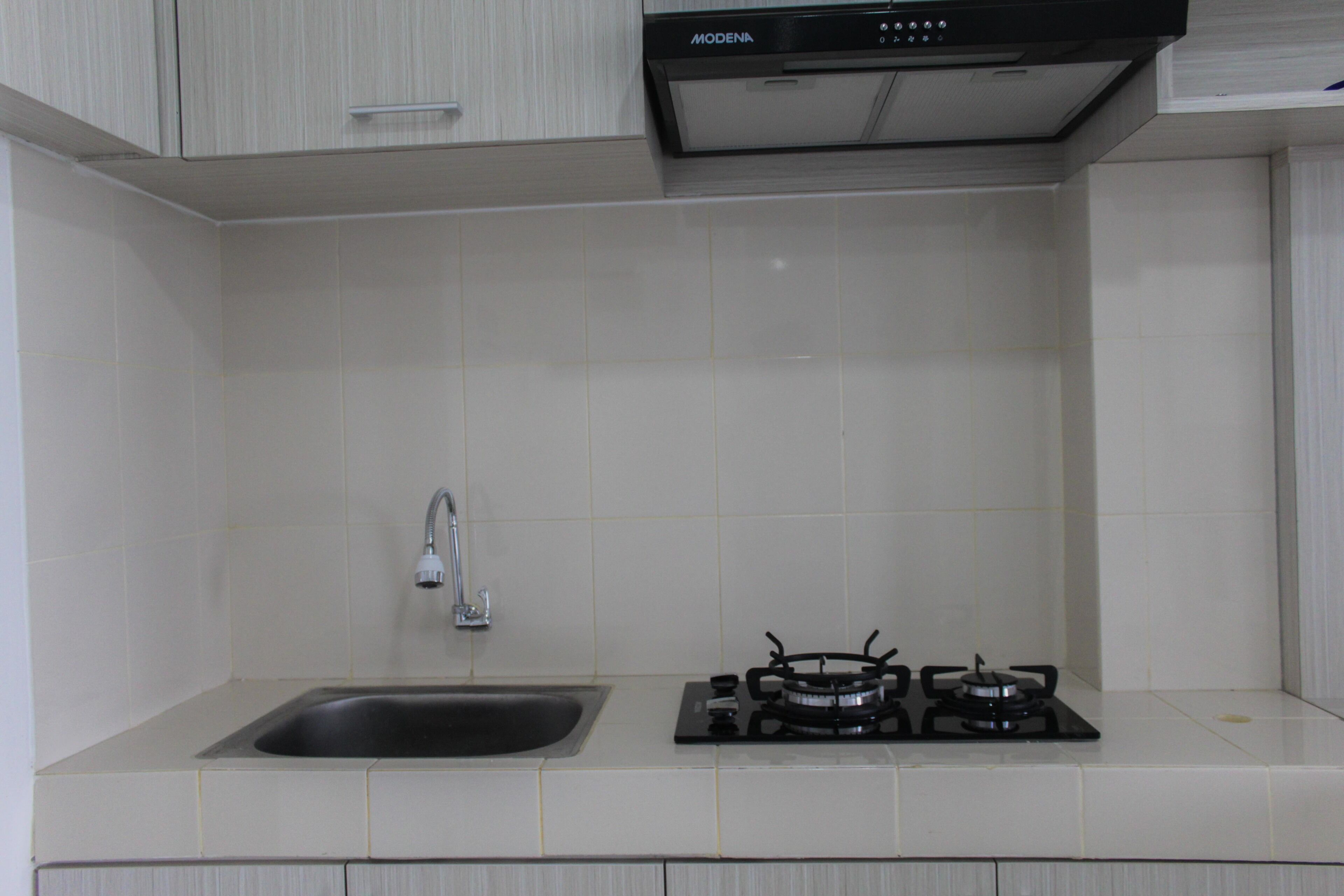 A kitchen with a sink, a gas stove, and a modern range hood.