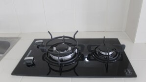 A black gas stove with four burners and a control panel. - Comfort Studio Apartment at Urban Heights Residences (South Tangerang)