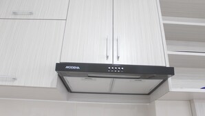 A kitchen with white cabinetry and a black range hood labeled 'MODENA'. - Comfort Studio Apartment at Urban Heights Residences (South Tangerang)