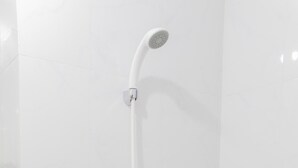 A shower with a curved head and a long handle, mounted on a tiled wall. - Comfort Studio Apartment at Urban Heights Residences (South Tangerang)