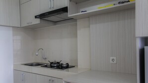 A kitchen with a sink, stove, and cabinets. - Comfort Studio Apartment at Urban Heights Residences (South Tangerang)