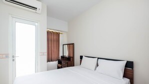 A hotel room with a bed, a dresser, a mirror, and an air conditioning unit. - Comfortable Studio at Springlake Summarecon Bekasi Apartment (Bekasi)
