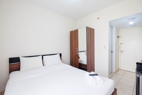Una habitación de hotel con cama, armario, espejo y puerta.