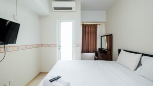 A hotel room with a bed, a television mounted on the wall, a door leading to a bathroom, and a window with curtains. - Comfortable Studio at Springlake Summarecon Bekasi Apartment (Bekasi)