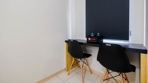 A small room with a black desk, two black chairs, a window, and a travel-themed box on the desk. - Comfortable Springlake Summarecon Studio Apartment near Mall (Bekasi)