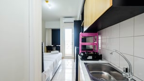 A compact hotel room with a kitchenette, a bed, and a bathroom. - Comfortable Springlake Summarecon Studio Apartment near Mall (Bekasi)