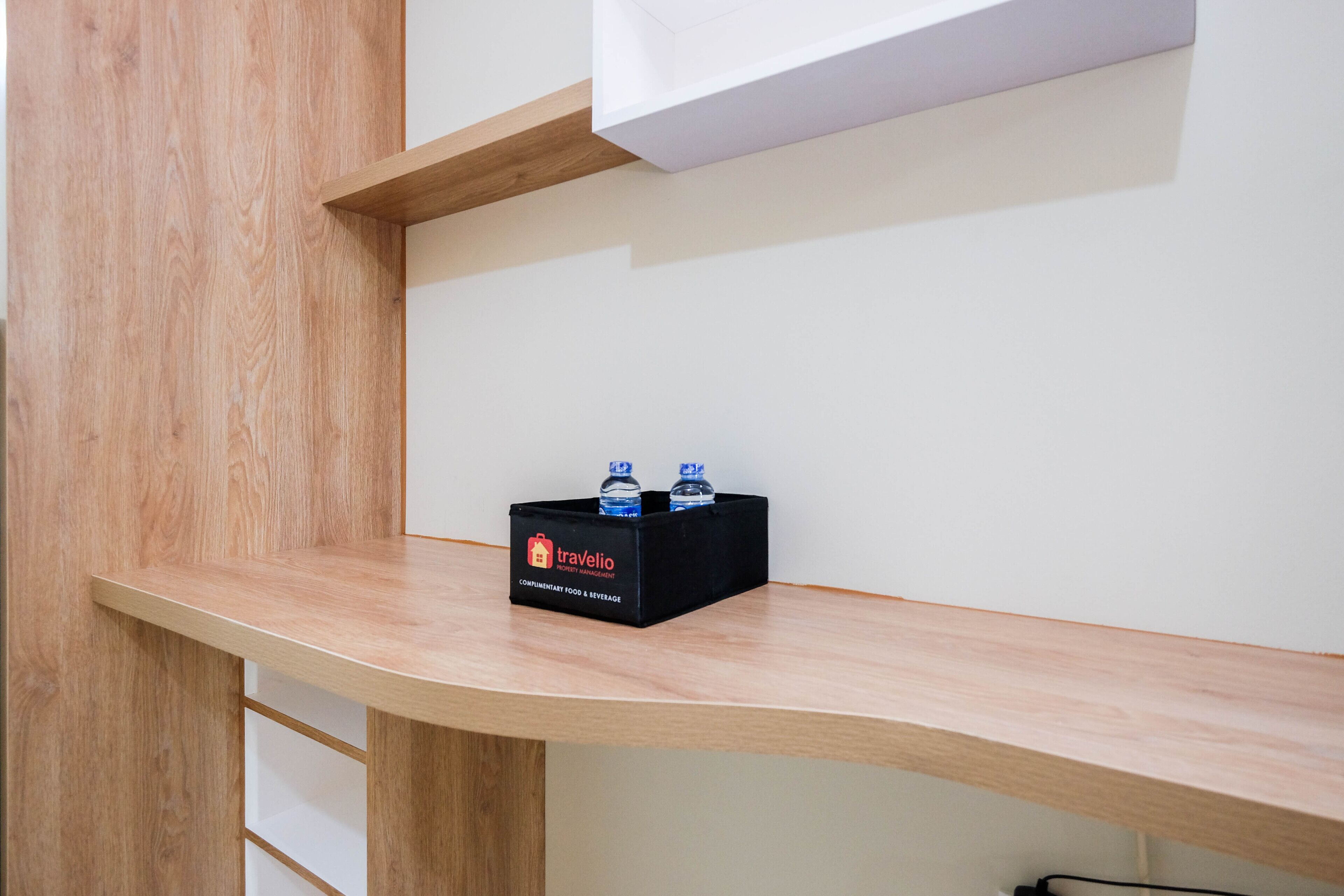 A wooden shelf with a black box labeled 'Travelio' containing two bottles.