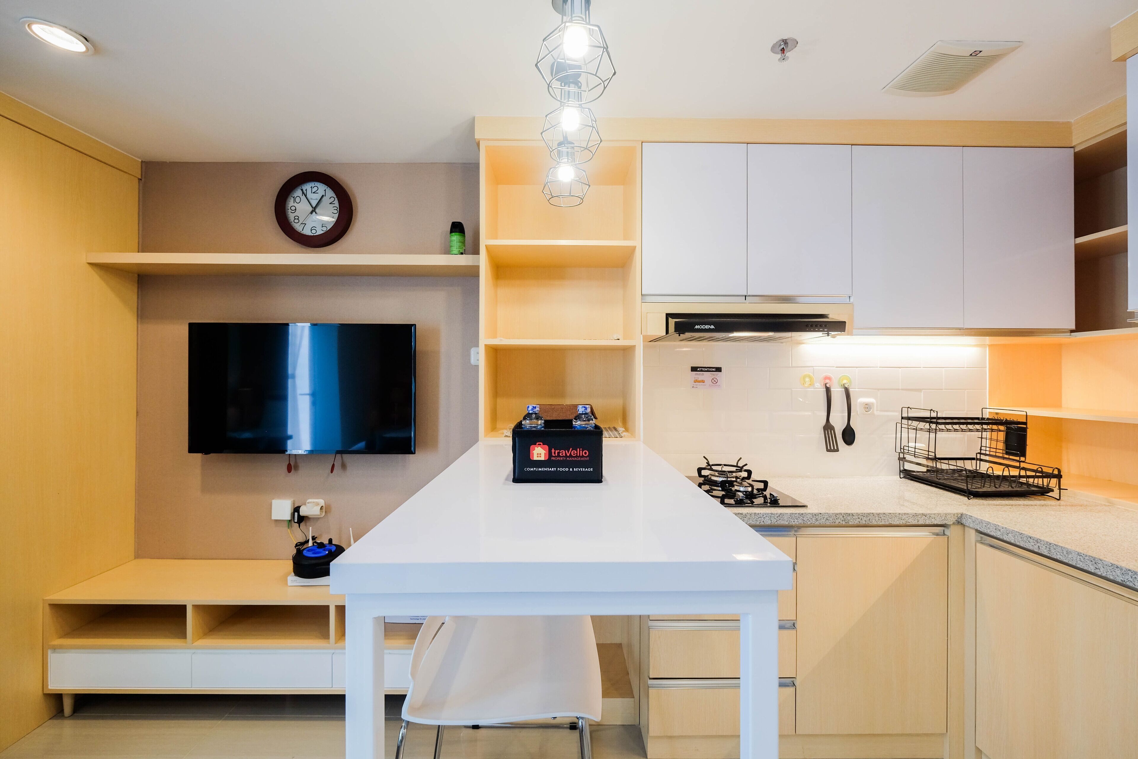 A modern kitchen with a central island, a flat-screen TV, and a built-in oven.