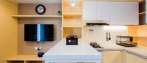A modern kitchen with a central island, a flat-screen TV, and a built-in oven.