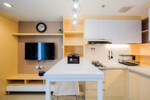 Een moderne keuken met een centraal eiland, een flatscreen televisie en een inbouwoven.