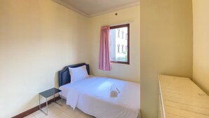 Une petite chambre propre, avec un lit simple, une table de chevet et une fenêtre avec des rideaux.