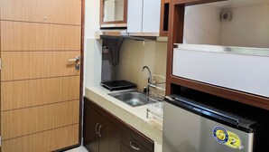 A compact kitchen with wooden cabinets, a stainless steel refrigerator, and a sink.