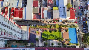 An aerial view of a commercial area with multiple buildings, a parking lot, and a swimming pool. - Homey and Comfy 2BR at Vida View Apartment (Makassar)