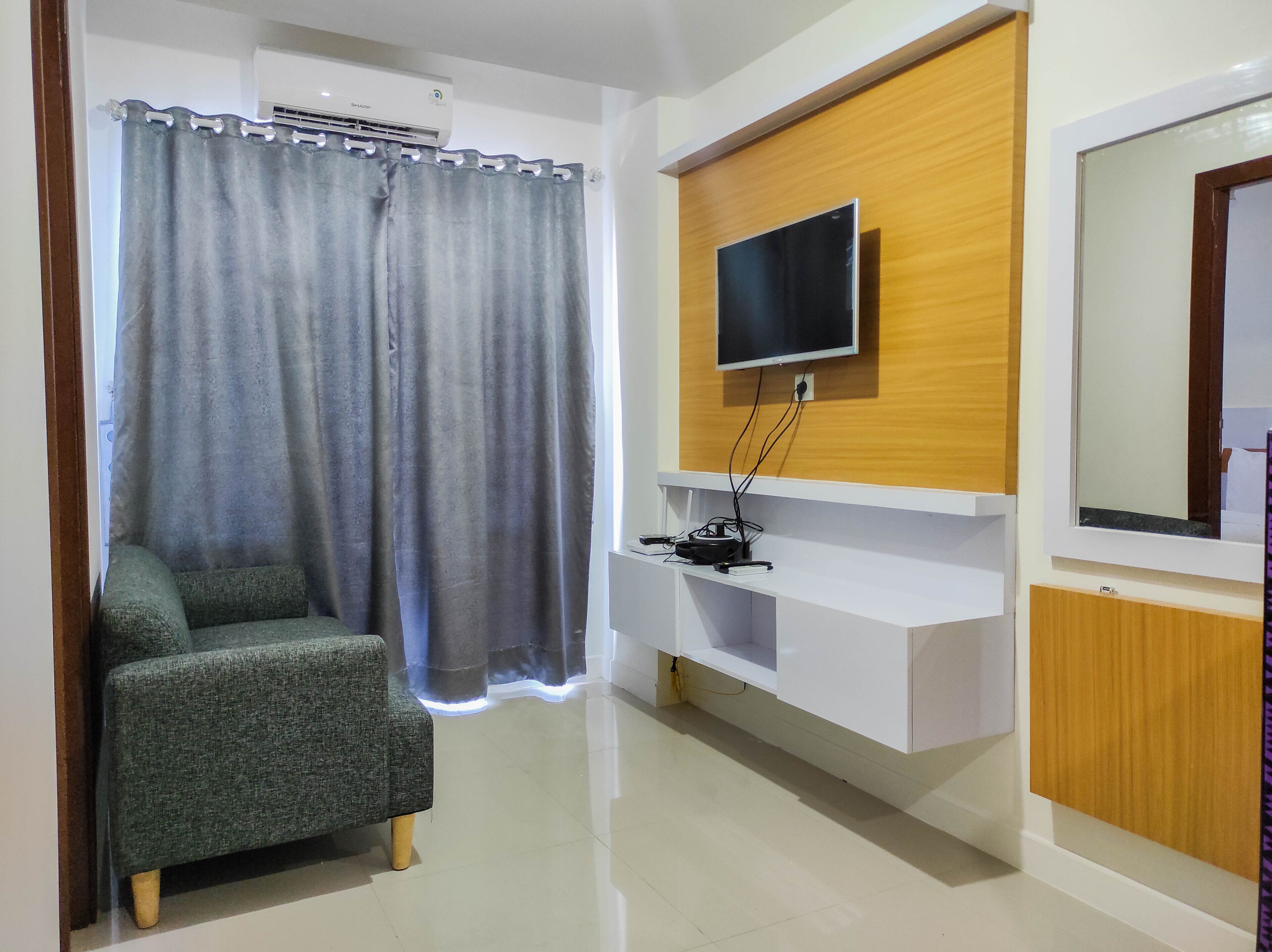 Un salon moderne avec un canapé gris, un téléviseur fixé au mur et un mur d’accent en bois.