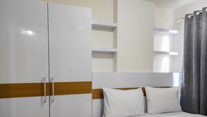 A hotel room with a bed, white wardrobe, and a shower curtain. - Homey and Comfy 2BR at Vida View Apartment (Makassar)