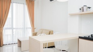Una habitación moderna y minimalista con kitchenette, un sofá y una zona de comedor.