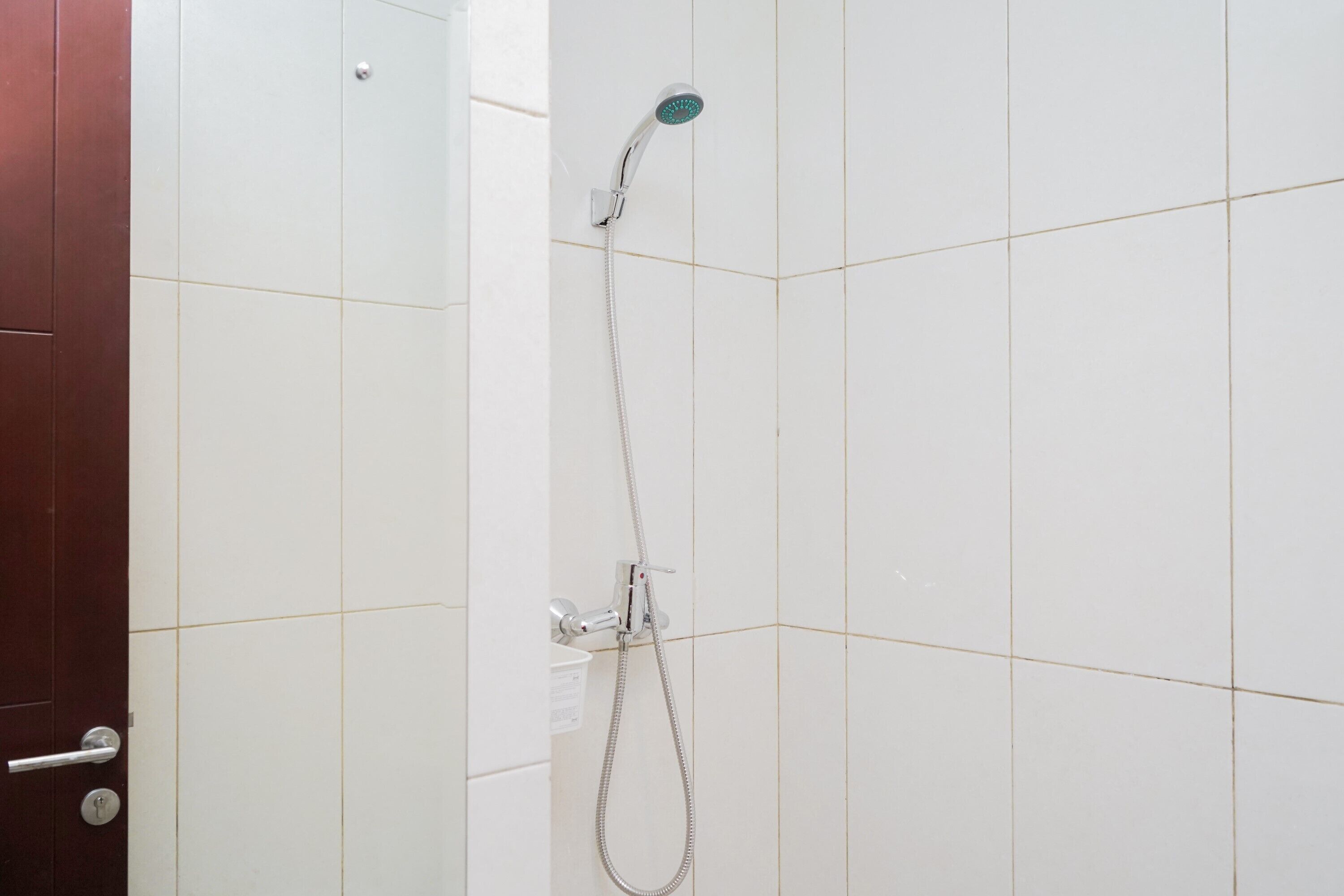 Eine Dusche mit Duschbrause und Wandarmatur.