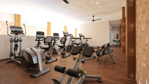 Un gimnasio con diverso equipo de ejercicio, incluyendo cintas de correr, bicicletas estáticas y máquinas de pesas.