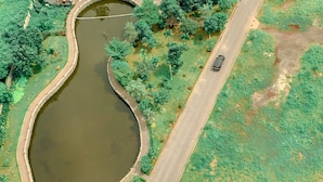 Une vue aérienne d’une route qui serpente autour d’une étendue d’eau, avec de la végétation et des arbres de part et d’autre.