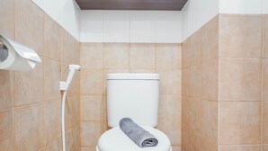 Une salle de bain équipée de toilettes, d’une serviette et d’un sèche-mains.