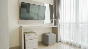 Quarto moderno com televisão na parede, console de madeira e um pequeno banquinho.