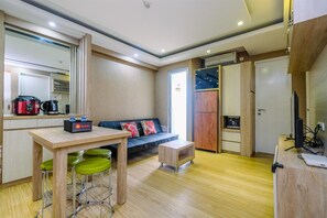 A compact kitchen with a dining area, a sofa, and a small table. - Modern 2BR at Bassura City Apartment (Jakarta)