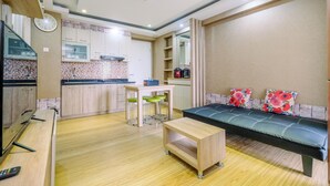 A compact living space with a kitchenette, a dining area, and a sofa with floral cushions. - Modern 2BR at Bassura City Apartment (Jakarta)