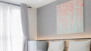 Une chambre d’hôtel moderne avec un grand lit, une tête de lit en bois, une table de chevet et un climatiseur fixé au mur.