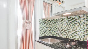 A kitchen with a tiled backsplash, a gas stove, and a stainless steel sink. - Elegant 2BR at Bassura City Apartment (Jakarta)