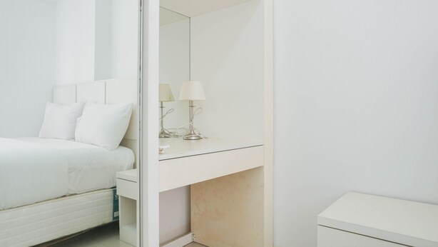 A modern bedroom with a bed, a bedside table, a mirror, and a nightstand. - Elegant 2BR at Bassura City Apartment (Jakarta)