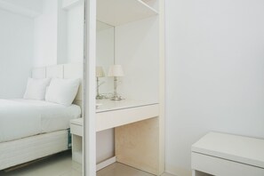 Quarto moderno com cama, mesa de cabeceira, espelho e criado-mudo.