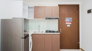 A compact kitchen with a stainless steel refrigerator, a gas stove, and wooden cabinets.