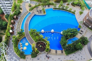 A large circular pool with surrounding greenery and seating areas. - Scenic Studio at West Vista Apartment Puri (Jakarta)