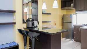 Une cuisine moderne dotée d’un îlot central, d’appareils électroménagers en acier inoxydable et de luminaires suspendus.