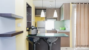 Une cuisine moderne dotée d’un îlot central, de tabourets de bar, de luminaires suspendus et offrant une vue sur l’espace de vie.