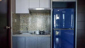 A compact kitchen with a double-door refrigerator, a gas stove, and a tiled backsplash. - Exquisite & Spaciuos 1BR Apartment at Tamansari Papilio (Surabaya)