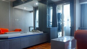A modern bathroom with a large mirror, a vanity with a sink, and a chair. - Exquisite & Spaciuos 1BR Apartment at Tamansari Papilio (Surabaya)