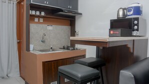 A compact kitchenette with a stove, sink, and a microwave. There are two stools and a small countertop. - Brand New and Best Choice 2BR at Cinere Resort Apartment (Depok)