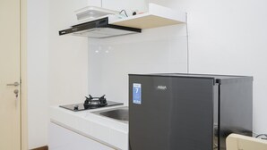 A compact kitchen with white cabinetry, a black refrigerator, a built-in stove, and a stainless steel sink. - Comfort with Garden View Studio Apartment M-Town Residence (Gading Serpong)