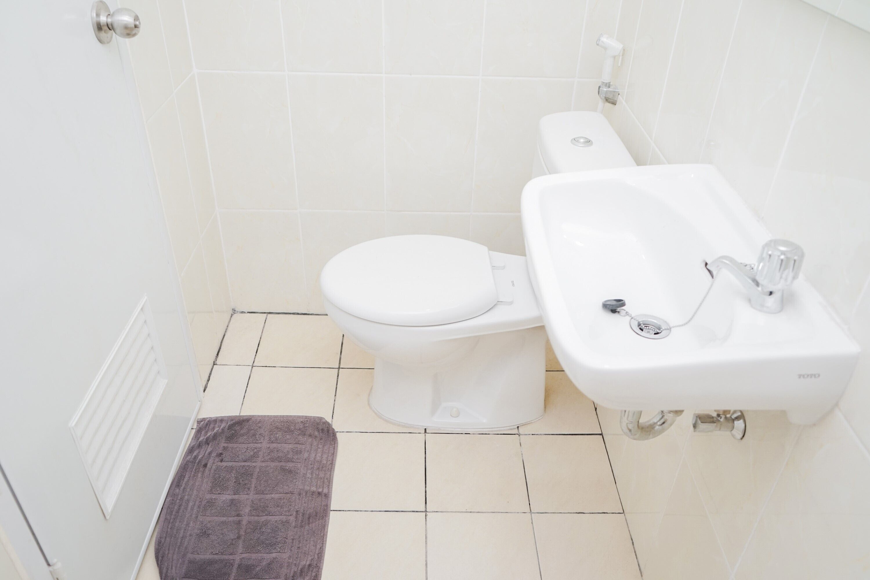 A bathroom with a toilet, sink, and a towel on the floor.