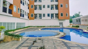 A residential building with a swimming pool, balconies, and a garden area. - Cozy and Simply Studio Apartment at Urban Heights Residences (South Tangerang)