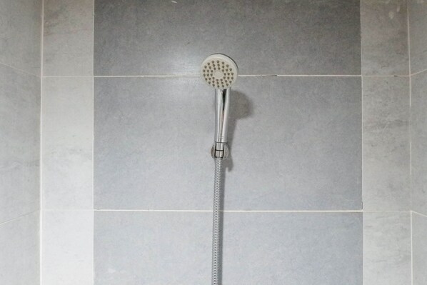 A showerhead mounted on a tiled wall.