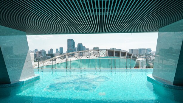 Ein Pool ohne Ende mit Blick auf eine Stadtlandschaft, moderne Architektur und einer Glasufernung.