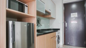 Eine kleine Küche mit einem Edelstahl-Kühlschrank, einer Mikrowelle und einer Waschmaschine.