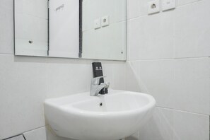 A white bathroom sink with a mirror above it, a faucet, and a soap dispenser.