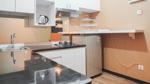 Eine kleine Küche mit weißen Schränken, einer Edelstahl-Spüle, einem eingebauten Herd und einem kleinen Kühlschrank.
