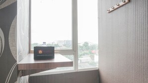 Ein Zimmer mit Fenster, einer Holzablage mit einer Kiste mit dem Aufdruck 'Travelio' und einem Wandhaken.