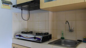 A kitchen with a gas stove, a sink, and a range hood. - Comfy and Best View 2BR at Serpong Greenview Apartment (South Tangerang)
