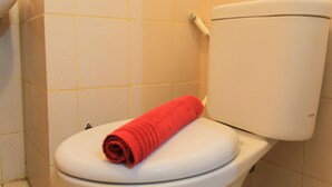 A toilet with a white seat and tank, and a red towel placed on the seat. - Comfy and Best View 2BR at Serpong Greenview Apartment (South Tangerang)